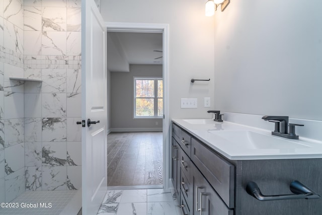 bathroom with marble finish floor, double vanity, a sink, and baseboards