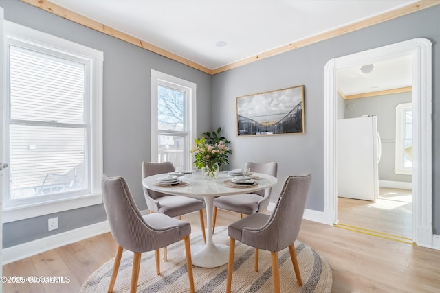 dining room featuring ornamental molding, light wood-style flooring, and baseboards