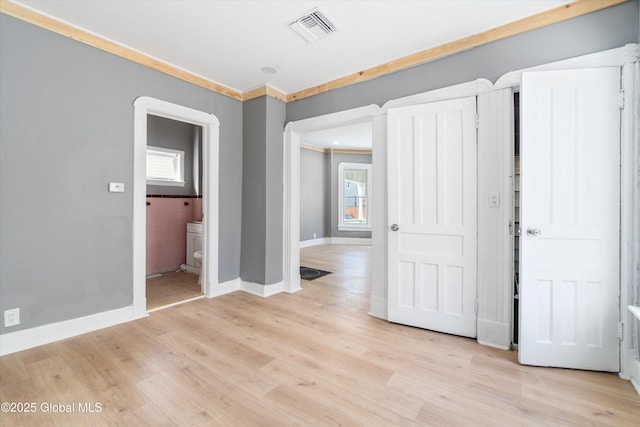 spare room featuring a healthy amount of sunlight, light wood-style floors, baseboards, and visible vents