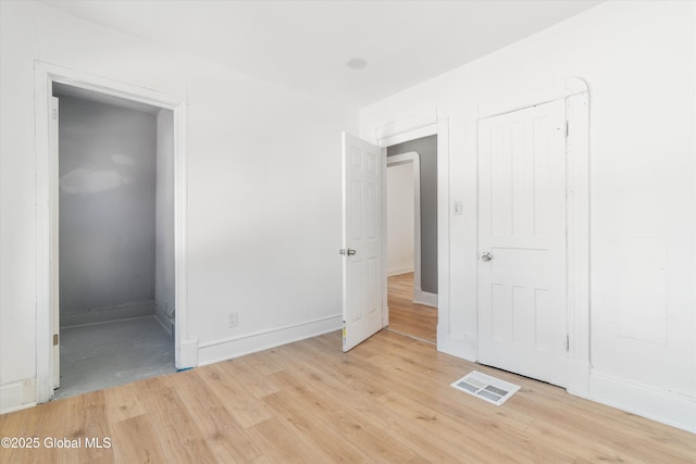 unfurnished bedroom with light wood-style floors, visible vents, and baseboards