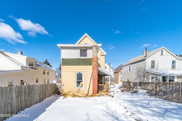 snow covered rear of property with fence and a residential view