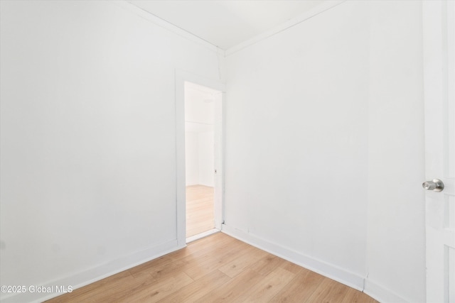 spare room with light wood finished floors, baseboards, and ornamental molding