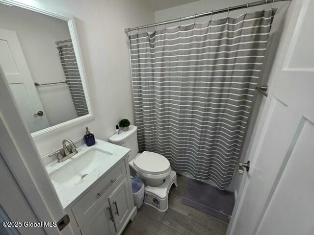 bathroom featuring toilet, wood finished floors, and vanity