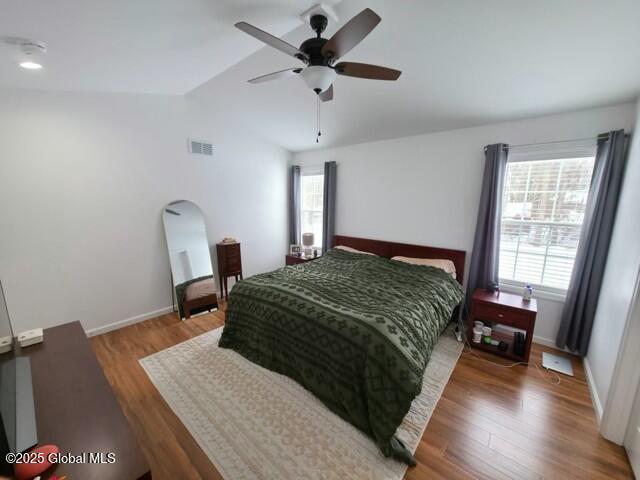 bedroom with lofted ceiling, baseboards, visible vents, and wood finished floors