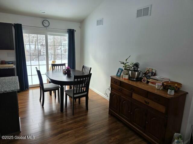 dining space featuring baseboards, vaulted ceiling, visible vents, and dark wood finished floors