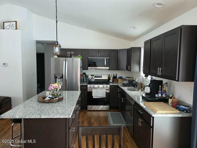 kitchen with a kitchen island, a sink, vaulted ceiling, appliances with stainless steel finishes, and dark wood finished floors