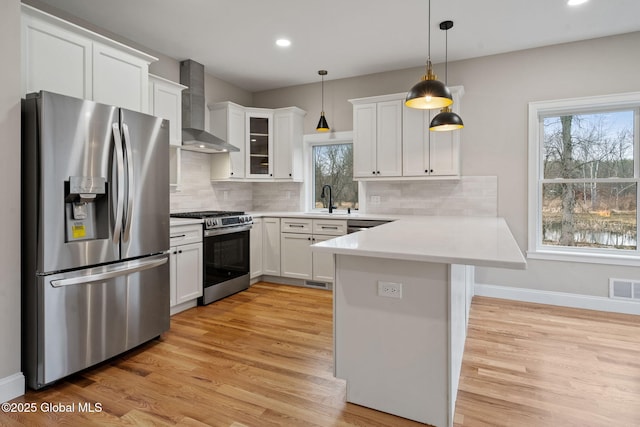706 Swaggertown Rd, Charlton, NY 12302 - kitchen with stainless steel appliances, wall chimney range hood, a sink, a peninsula, and light wood-style flooring