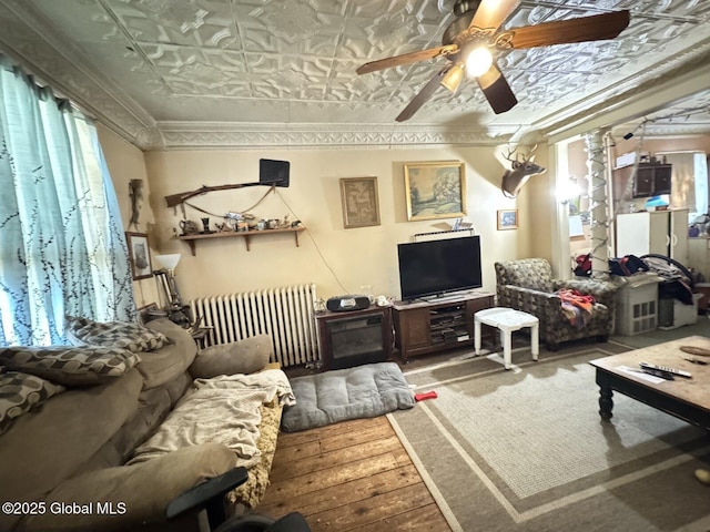 living room with ceiling fan, wood finished floors, a wealth of natural light, radiator, and an ornate ceiling