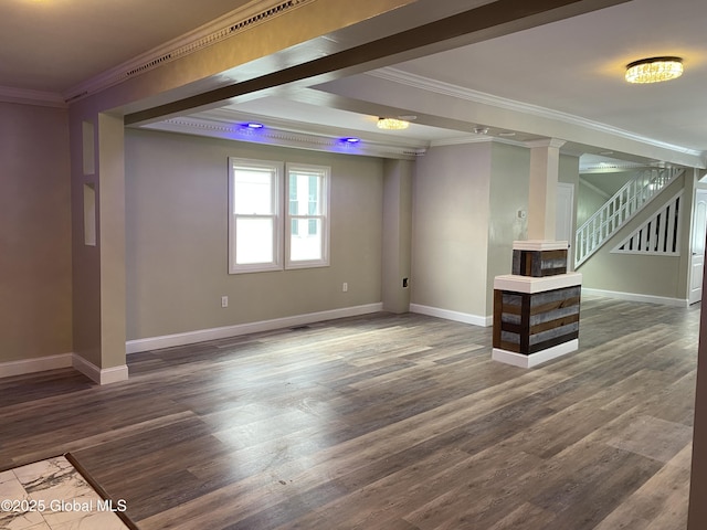 below grade area with ornamental molding, dark wood-style flooring, stairway, and baseboards