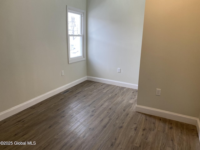 empty room featuring baseboards, visible vents, and wood finished floors