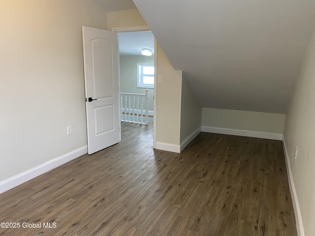 bonus room with dark wood-style floors, lofted ceiling, and baseboards