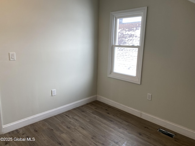 unfurnished room with dark wood-style floors, a healthy amount of sunlight, visible vents, and baseboards