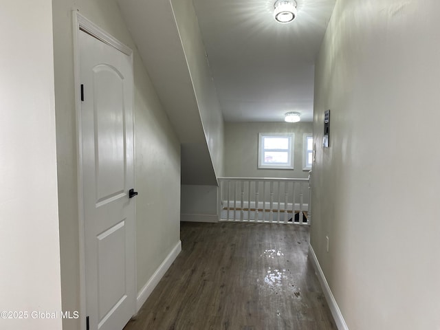 corridor with dark wood-style flooring and baseboards