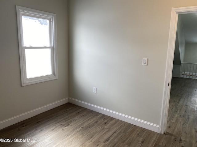 empty room with plenty of natural light, baseboards, and wood finished floors