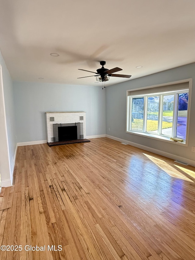 unfurnished living room featuring light wood-style floors, visible vents, a fireplace, and baseboards