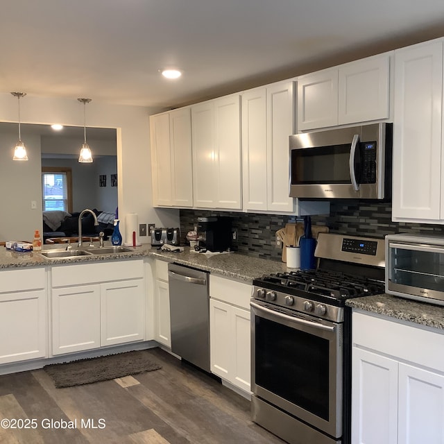 kitchen with a toaster, white cabinets, appliances with stainless steel finishes, a sink, and backsplash