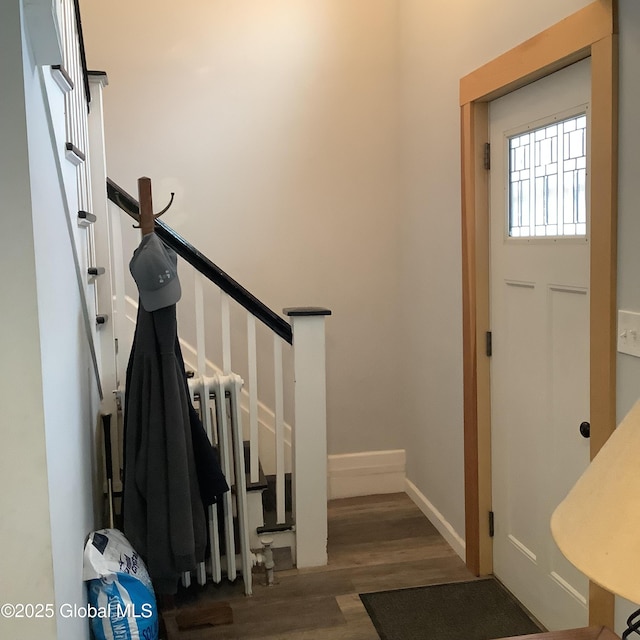 foyer with stairs, baseboards, wood finished floors, and radiator