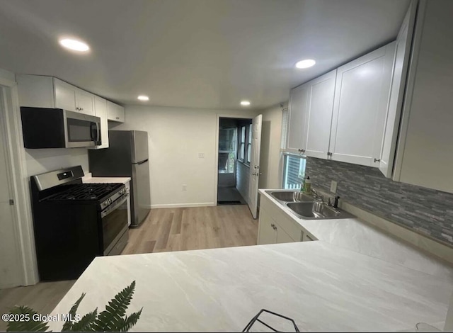 kitchen featuring tasteful backsplash, recessed lighting, appliances with stainless steel finishes, white cabinets, and a sink