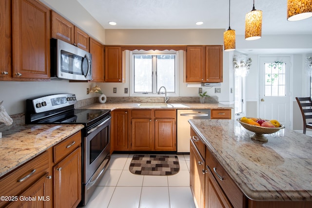 kitchen with a sink, a healthy amount of sunlight, appliances with stainless steel finishes, brown cabinetry, and pendant lighting