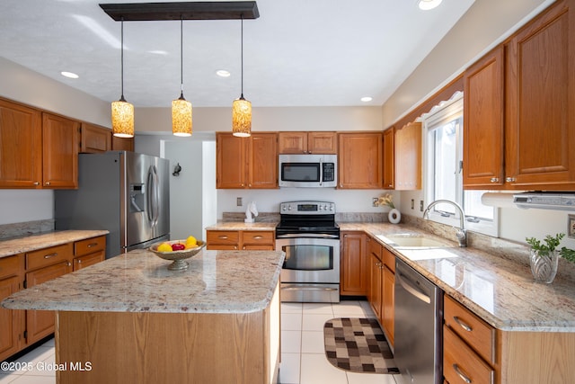 kitchen featuring a sink, a center island, appliances with stainless steel finishes, brown cabinets, and decorative light fixtures