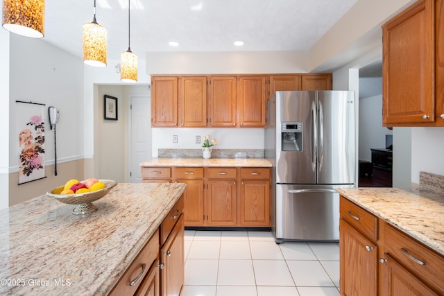 kitchen featuring light stone counters, brown cabinets, decorative light fixtures, and stainless steel fridge with ice dispenser