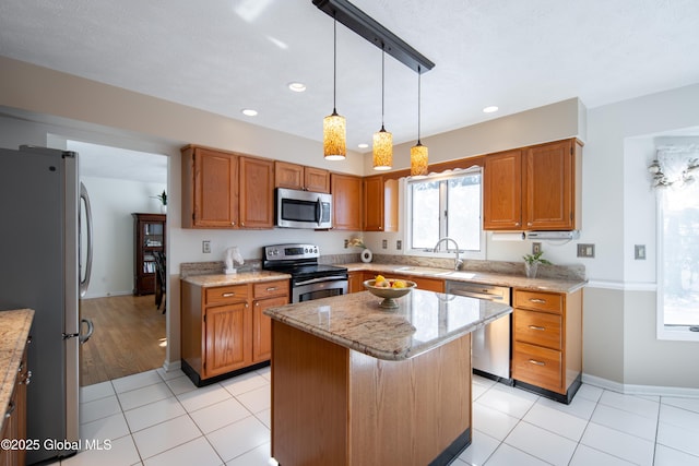 kitchen featuring a sink, appliances with stainless steel finishes, a center island, brown cabinetry, and decorative light fixtures