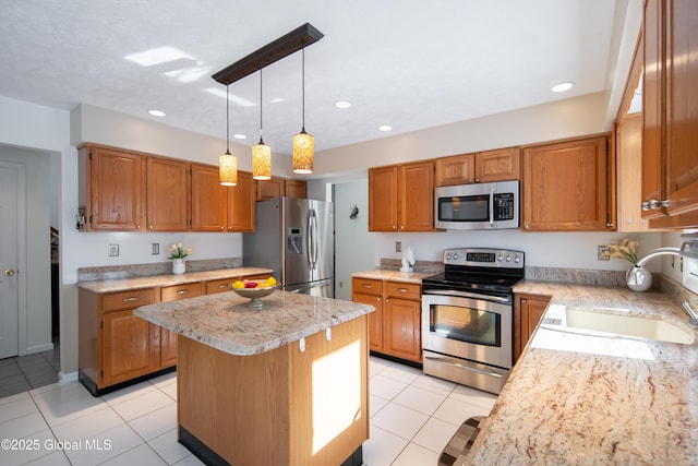 kitchen with a sink, a kitchen island, appliances with stainless steel finishes, brown cabinets, and pendant lighting