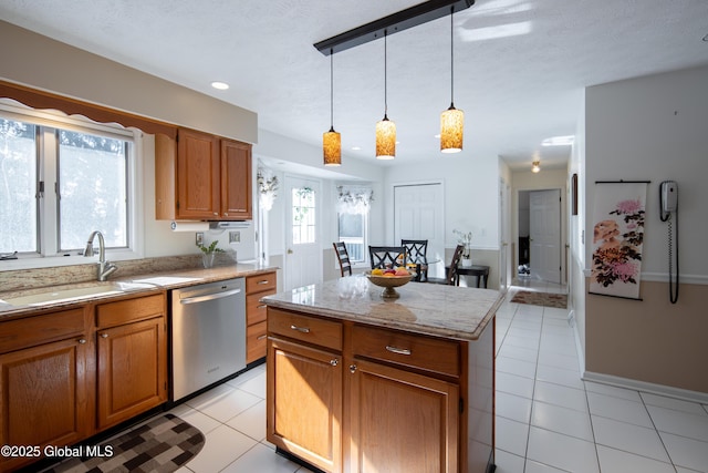 kitchen featuring brown cabinetry, dishwasher, a kitchen island, pendant lighting, and a sink