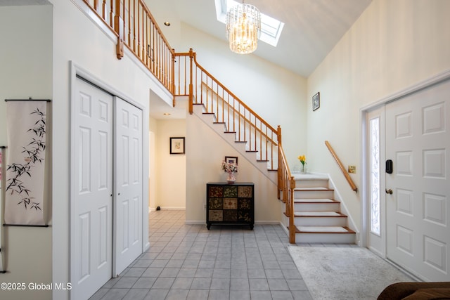 entrance foyer with a skylight, baseboards, stairway, a high ceiling, and light tile patterned flooring