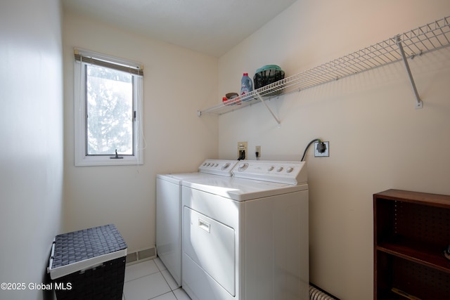 laundry room featuring light tile patterned floors, laundry area, washing machine and dryer, and baseboards