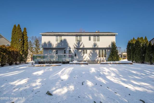 snow covered back of property featuring a deck