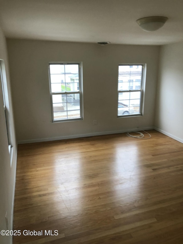 spare room featuring baseboards and wood finished floors
