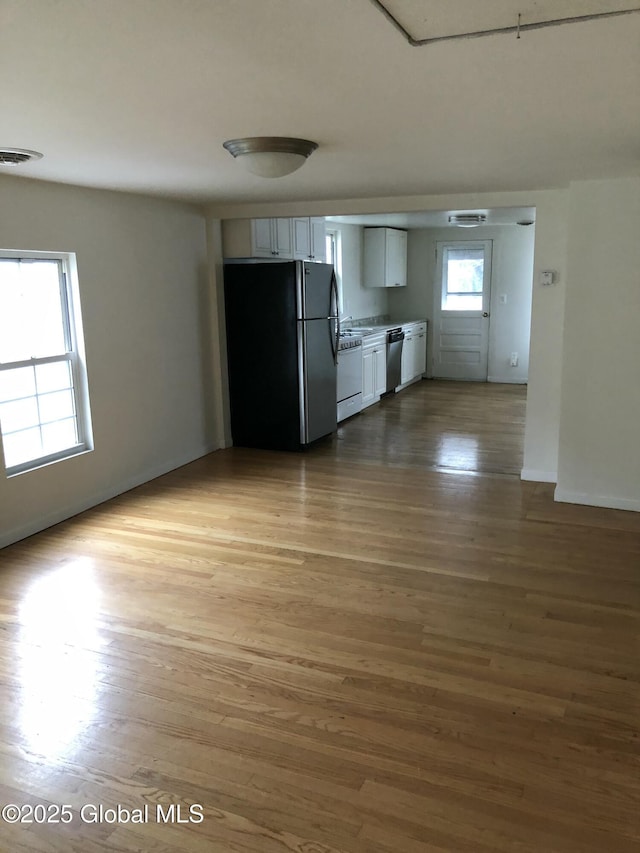 kitchen with freestanding refrigerator, wood finished floors, stainless steel dishwasher, dishwashing machine, and visible vents