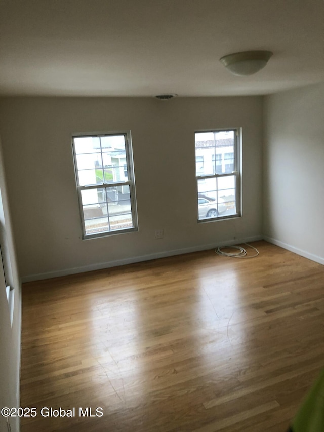 spare room with baseboards and wood finished floors