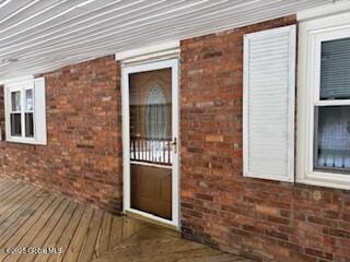 view of exterior entry with brick siding and a deck