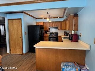 kitchen with brown cabinetry, range, freestanding refrigerator, a peninsula, and light countertops