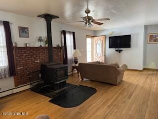 living room featuring ceiling fan, light wood-type flooring, and a wood stove