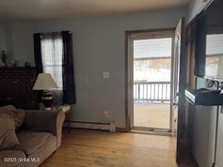 living area featuring light wood finished floors and a baseboard heating unit