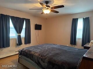 bedroom with dark wood-style flooring, ceiling fan, and baseboard heating