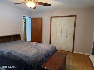 bedroom featuring ceiling fan, baseboards, a closet, and wood finished floors