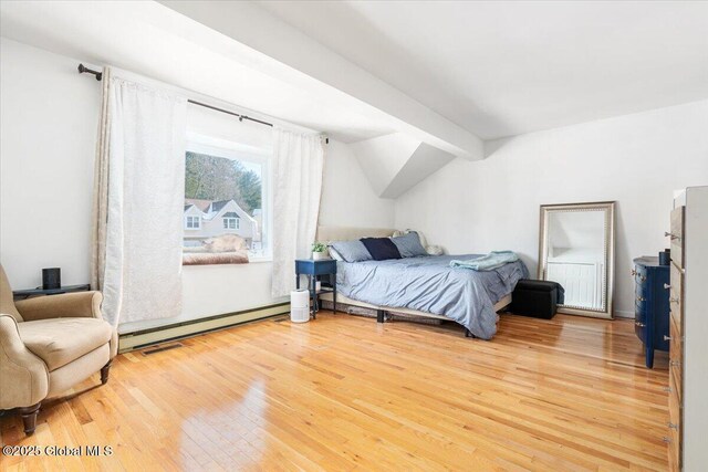 bedroom featuring a baseboard heating unit, lofted ceiling with beams, and wood finished floors