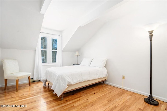 bedroom featuring vaulted ceiling, baseboards, and wood finished floors