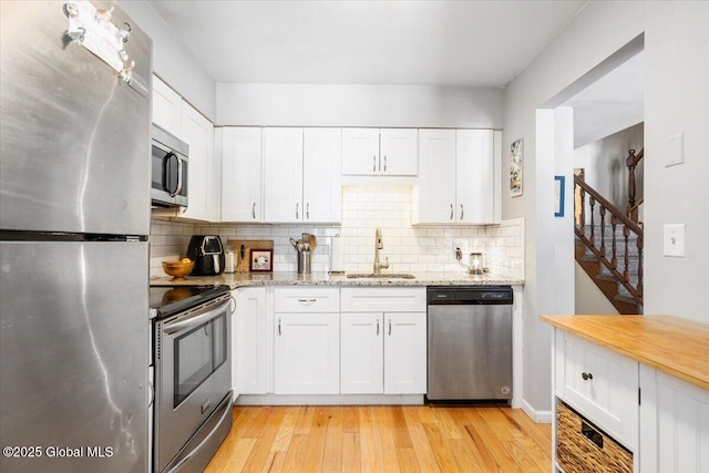 kitchen with stainless steel appliances, white cabinetry, and a sink