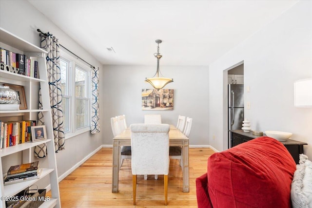 dining room featuring light wood finished floors and baseboards