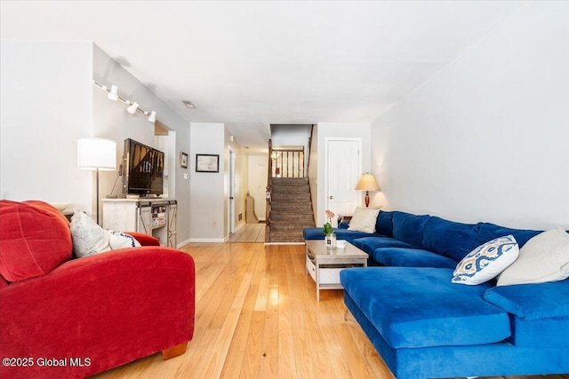 living room featuring wood finished floors, visible vents, and stairs