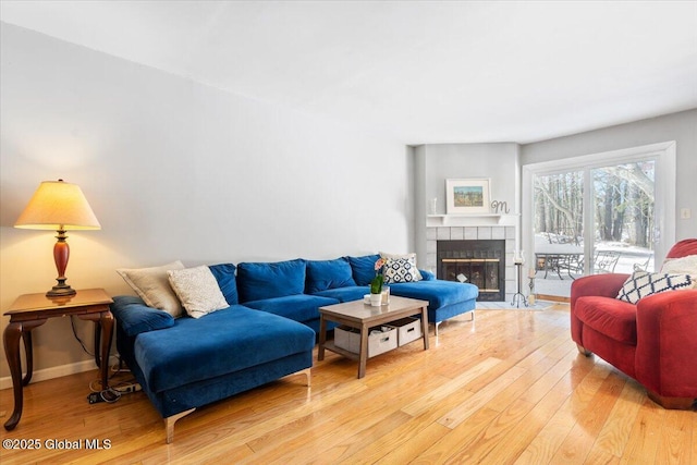 living area featuring a fireplace, light wood-style flooring, and baseboards