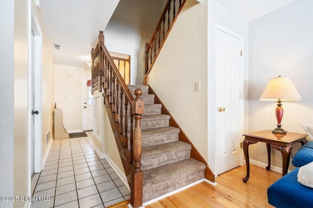 staircase featuring baseboards, visible vents, and wood finished floors