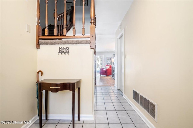 corridor featuring visible vents, baseboards, and light tile patterned floors