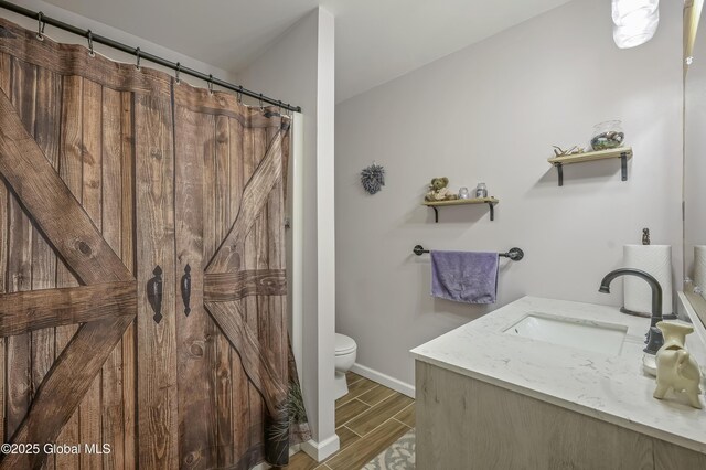 bathroom with wood tiled floor, baseboards, vanity, and toilet