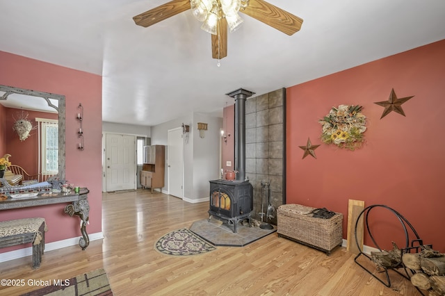 living room with a wood stove, baseboards, and wood finished floors